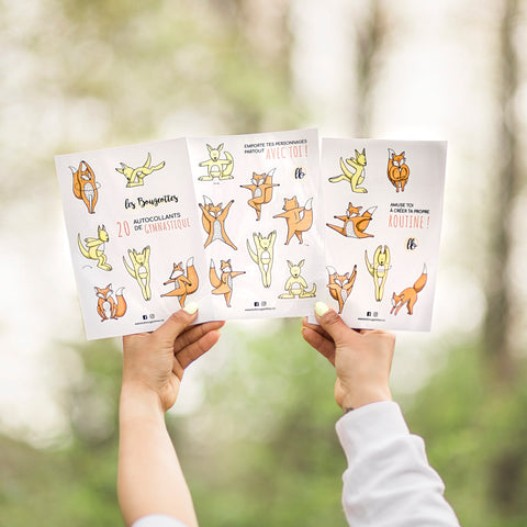Mains tenant trois feuilles d’autocollants Les Bougeottes avec renard et kangourou en différents mouvements de gymnastique.