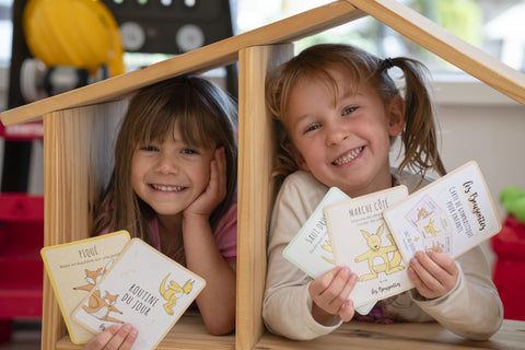 Deux enfants souriants jouent avec les cartes de gymnastique pour enfants Les Bougeottes, conçues pour développer la motricité et bouger en s’amusant.