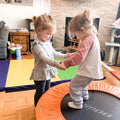 Un enfant sur le trampoline et qui tient les mains d'un autre jeune au sol durant un atelier de gymnastique en garderie