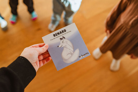 Une personne qui tient la carte du Renard des cartes d'apprentissage animaux polaire entouré d'enfants prêts  faire une pause active. 