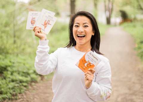 Femme asiatique entrepreneur ayant une entreprise qui fait bouger les jeunes: Les Bougeottes qui tien des cartes de gymnastique pour enfants.