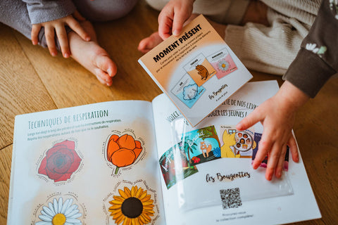 Livre interactif sur le moment présent où on voit des enfants sortir des cartes d'une pochette intégrée au livre.