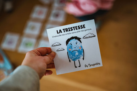 Cartes d'apprentissage des émotions (tristesse) dans la main d'une éducatrice 