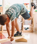 Poutre de gymnastique en bois dans une garderie avec un enfant réalisant le mouvement de l’aiguille.