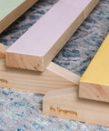 plusieurs poutres de gymnastique en bois pour enfants, de couleur verte, rose et jaune, disposées sur un tapis dans une garderie.