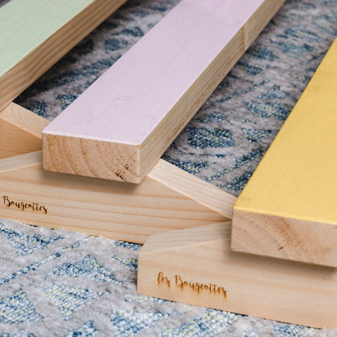 plusieurs poutres de gymnastique en bois pour enfants, de couleur verte, rose et jaune, disposées sur un tapis dans une garderie.